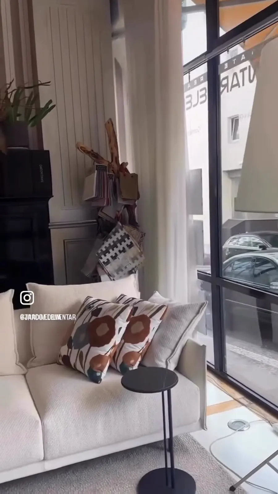 Papel de parede às riscas, estante com catálogos e sofá branco no atelier