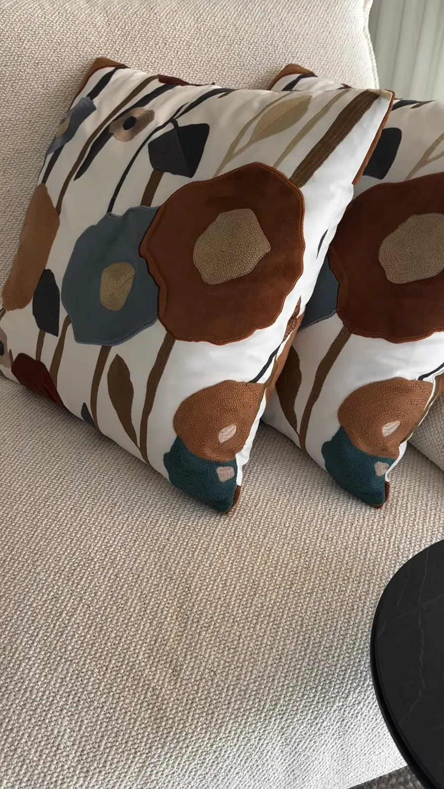Almofadas florais junto a uma mesa de apoio negra