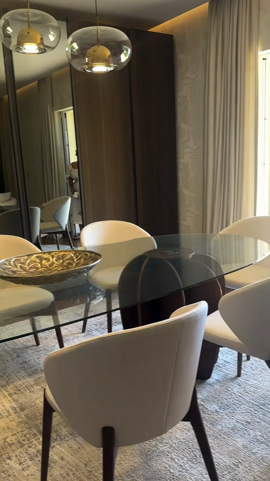 Mesa de jantar posta com cadeiras envolventes e candeeiros de vidro